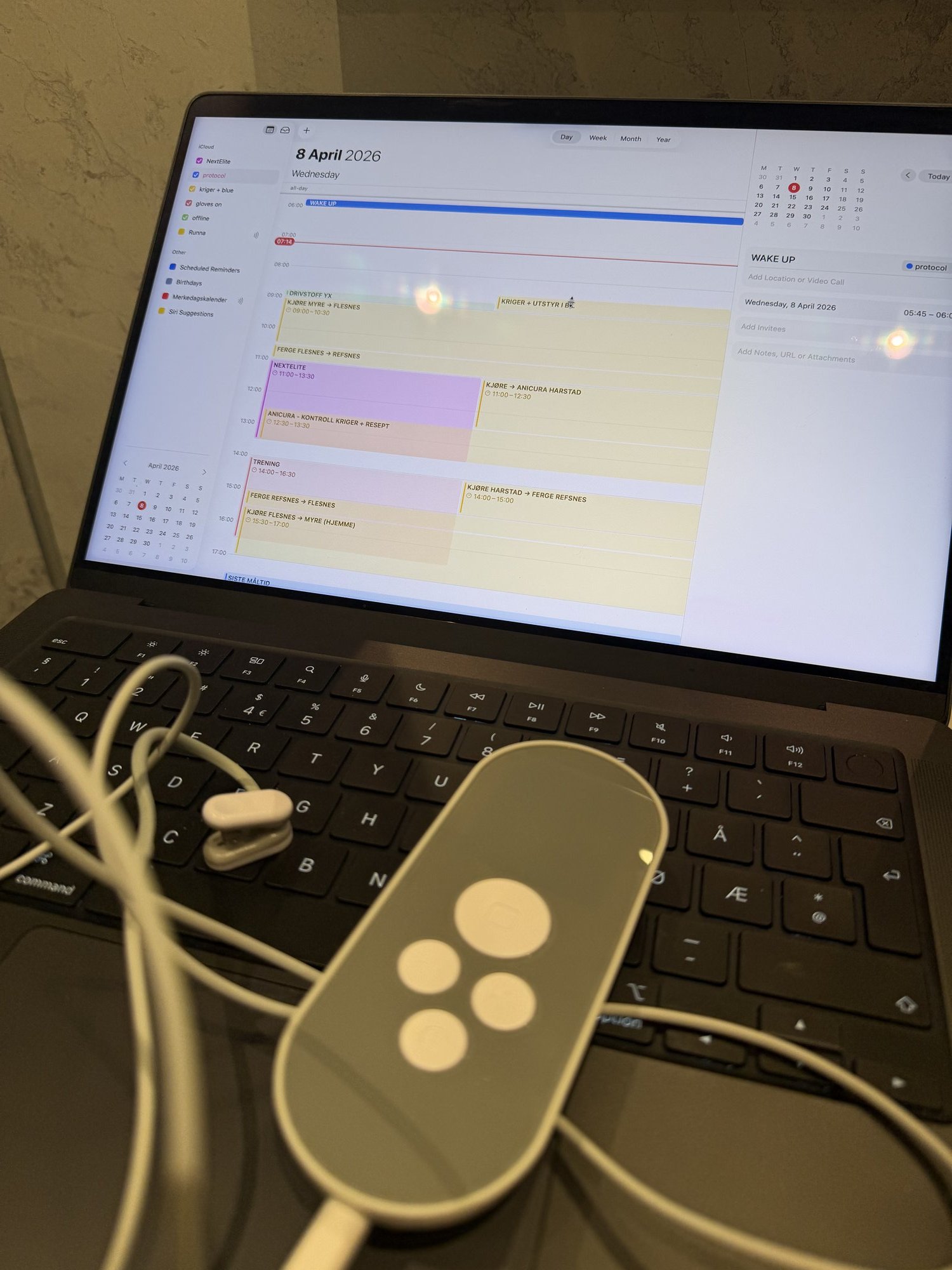Laptop med kalender åpen på 8. april, Nurosym vagusnervstimulator med ørepropper ved siden av