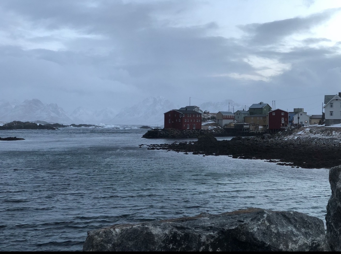 Fiskeværet Nyksund i vinterlys, røde hus ved havet, snødekte fjell bak